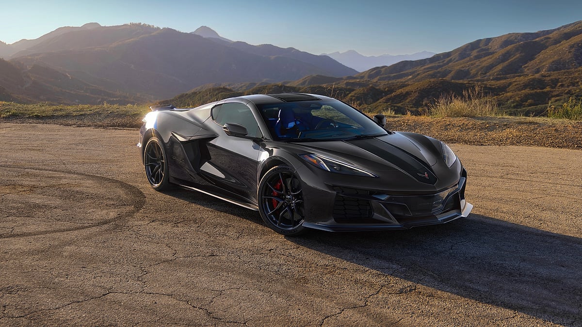A black Chevrolet Corvette GSX parked on a mountain road overlook at sunset.