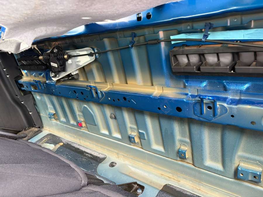 Toyota Tacoma rear cab wall with interior trim removed, showing exposed metal panels, wiring and ventilation components behind the rear seat.