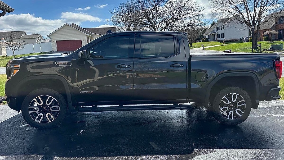 A 2020 GMC Sierra truck, with its large grille and GMC logo, is parked on an asphalt driveway in a Pennsylvania suburb