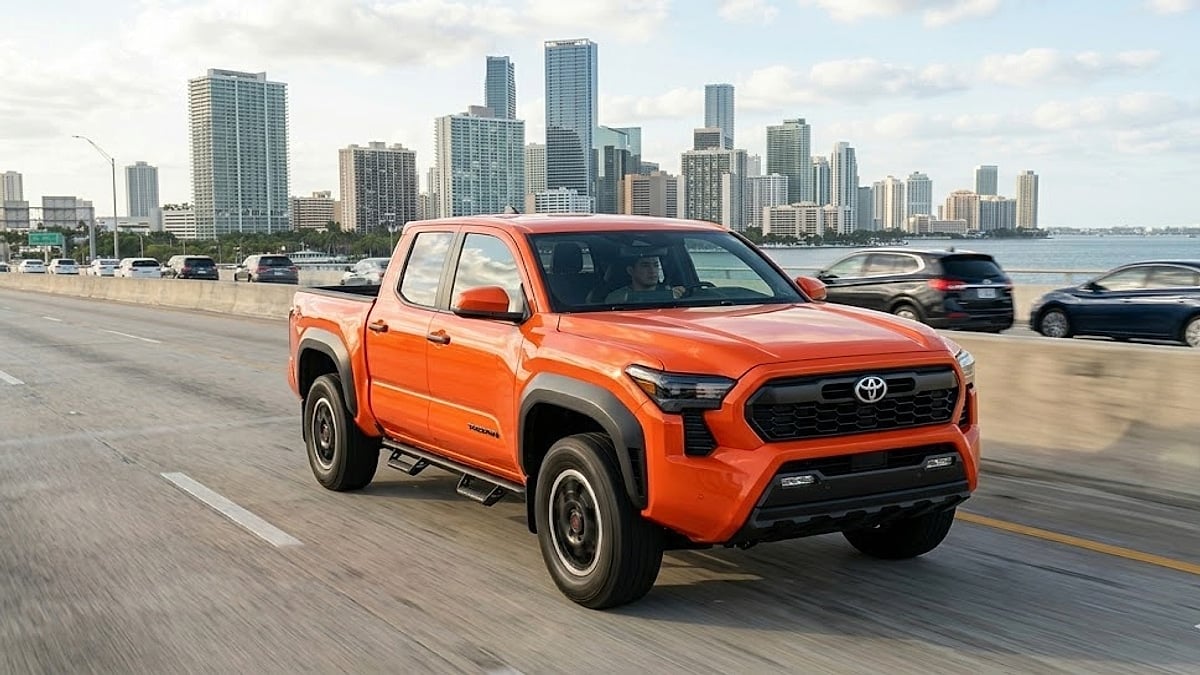 A Solar Octane 2025 Toyota Tacoma TRD Pro driving on a Miami highway, with high-value tailgate and city skyline