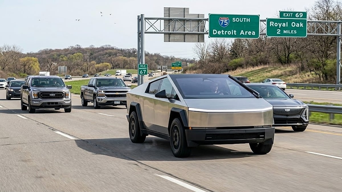 A Tesla Cybertruck drives on I-75 in Michigan, following traditional pickups near signs for Detroit and Royal Oak