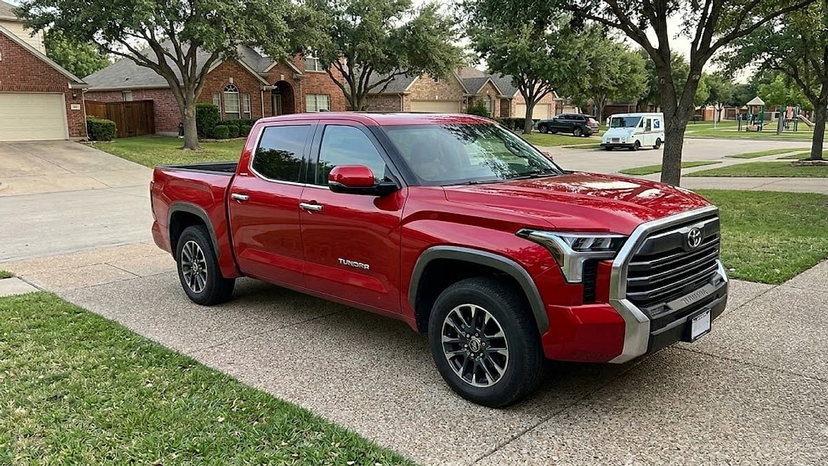 A clean, unobstructed front three-quarter view of a red 2023 Toyota Tundra parked on a concrete suburban driveway, showing no interior documents