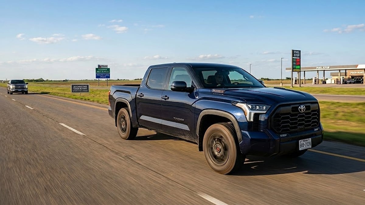 A dark blue 2026 Toyota Tundra i-FORCE MAX CrewMax truck drives dynamically through the wide, open landscape of Texas