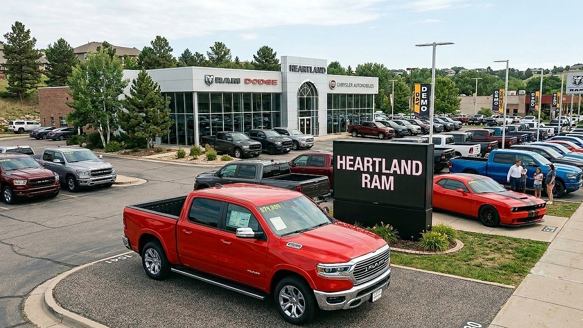 A detailed elevated view of the Heartland Ram Dodge dealership lot in Michigan, featuring new trucks, cars, and building signage under clear skies