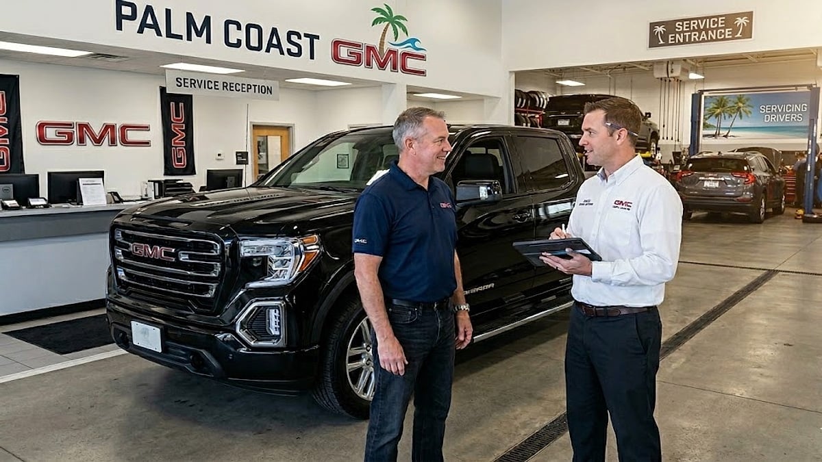 A local GMC owner discusses service at Palm Coast GMC with an advisor, next to a black GMC Sierra truck