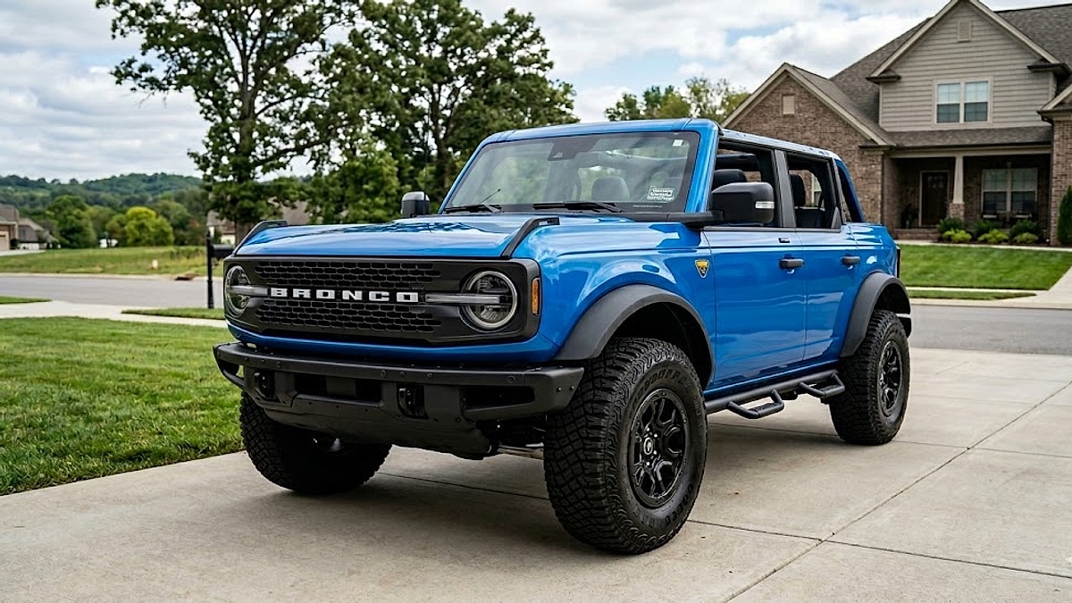 A photograph of a blue Ford Bronco Badlands Sasquatch parked in a suburban Tennessee driveway, highlighting its off-road features