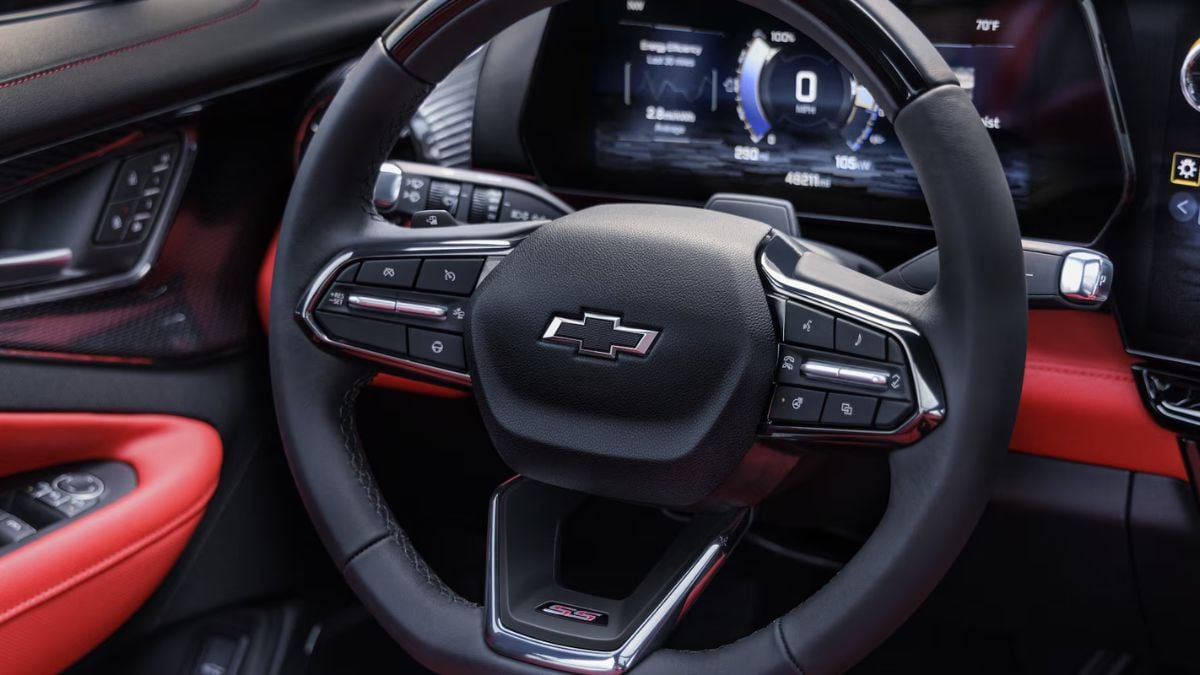 Black Chevrolet steering wheel with red leather interior, digital instrument cluster, close-up view