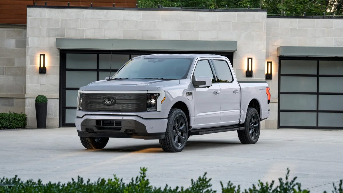 White Ford F-150 Lightning electric pickup truck parked in front of modern garage doors