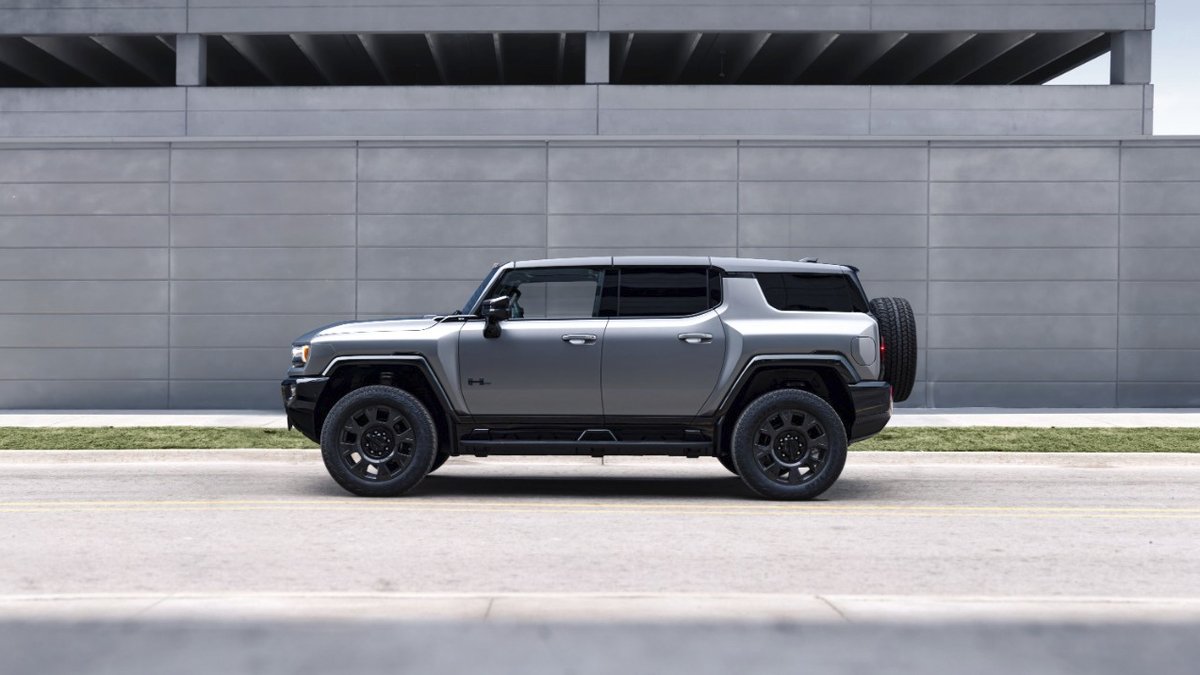 2026 GMC Hummer EV SUV side profile in metallic gray highlighting aggressive wheel arches and off-road tires