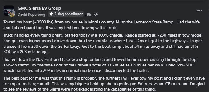 A GMC Sierra EV truck towing a boat, with family inside, parked at a boat ramp, showcasing electric vehicle towing capabilities.