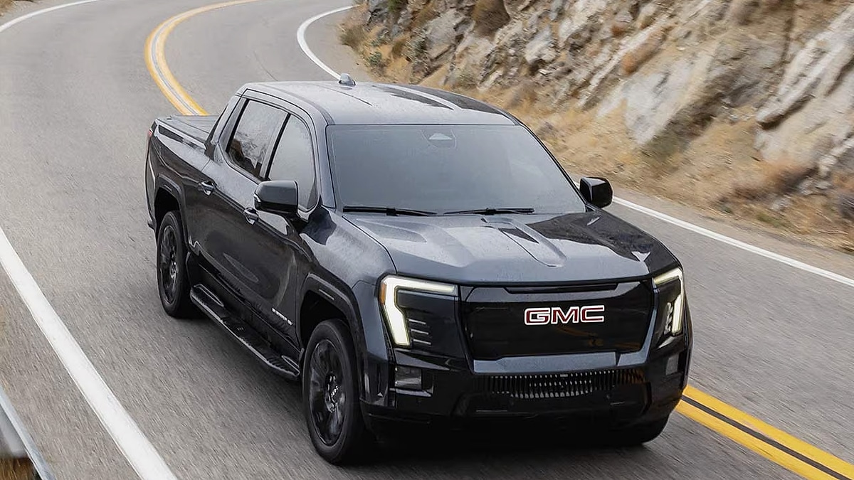 GMC Sierra EV electric pickup truck driving on a highway showing full side profile
