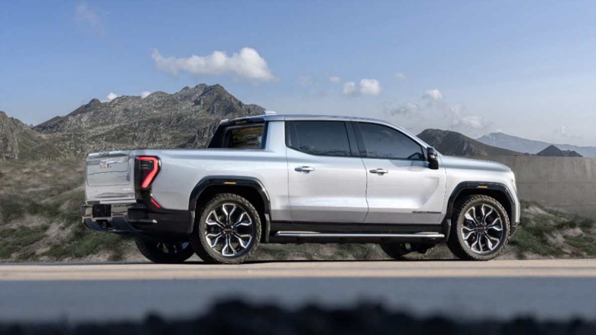 2025 GMC Sierra EV in white, side profile against rugged mountain landscape with bold black wheels and distinctive red-trimmed taillights
