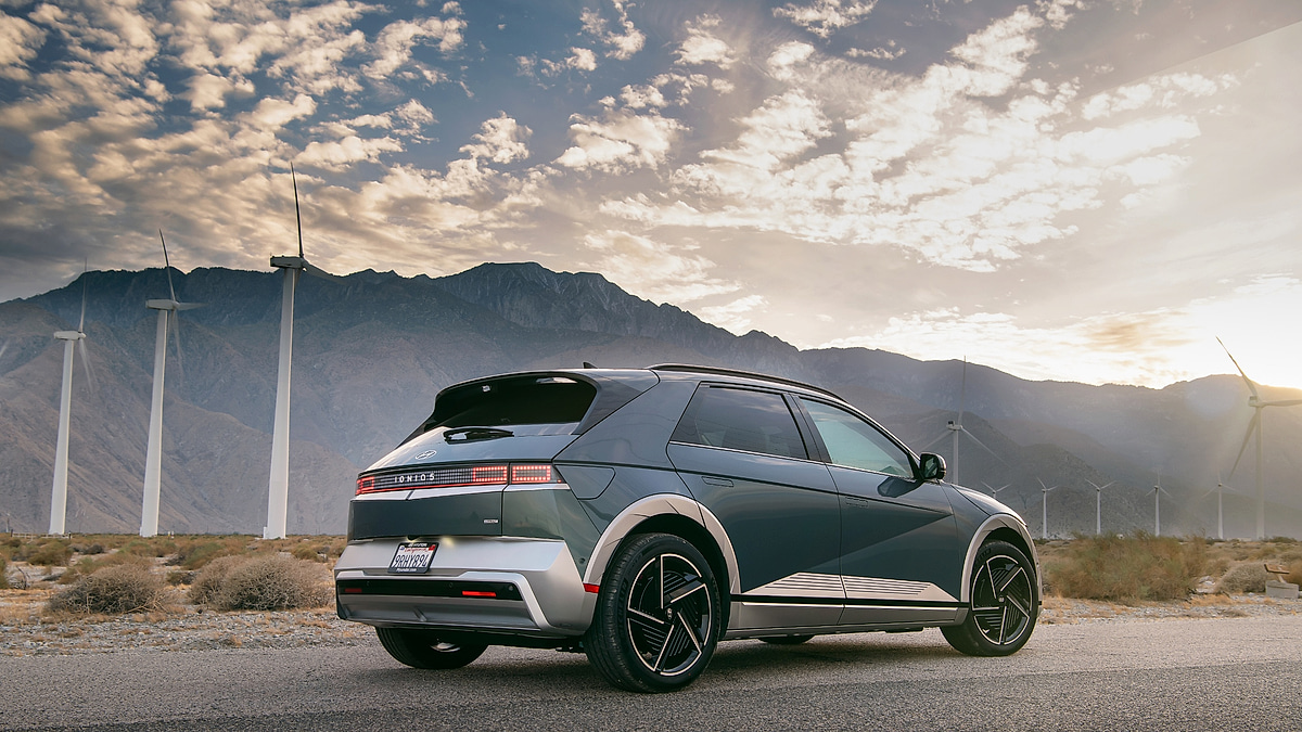 Hyundai IONIQ 5 parked near wind turbines with mountains in background