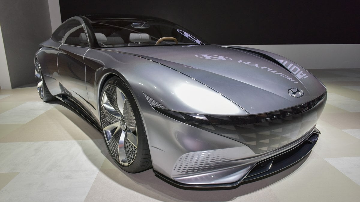 A futuristic silver Hyundai concept car with sleek lines and large wheels displayed in a modern showroom setting.