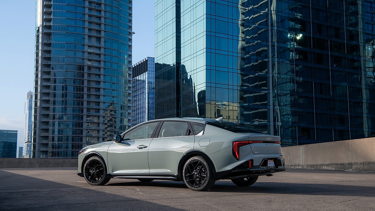 Kia K4 rear view parked with modern city skyline buildings