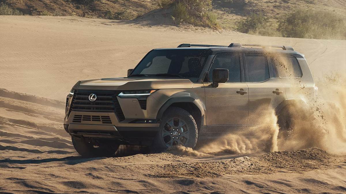 Lexus GX 550 SUV kicking up desert sand, driving diagonally across rugged terrain with dust clouds