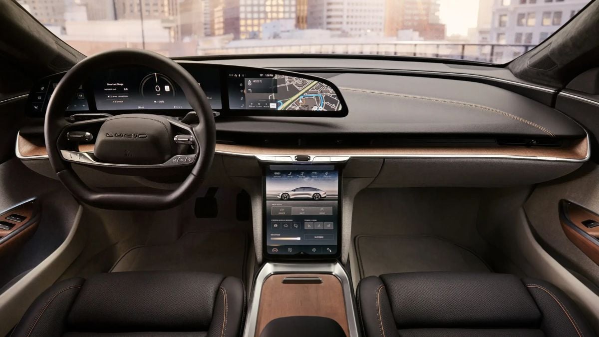 Lucid Air interior featuring a sleek dashboard with digital displays, modern steering wheel, wood accents, and touchscreen controls, urban skyline view.