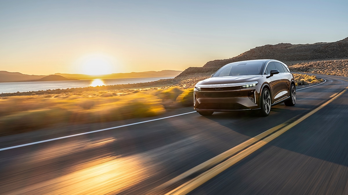 Lucid Gravity SUV driving on highway at sunset with mountains in background