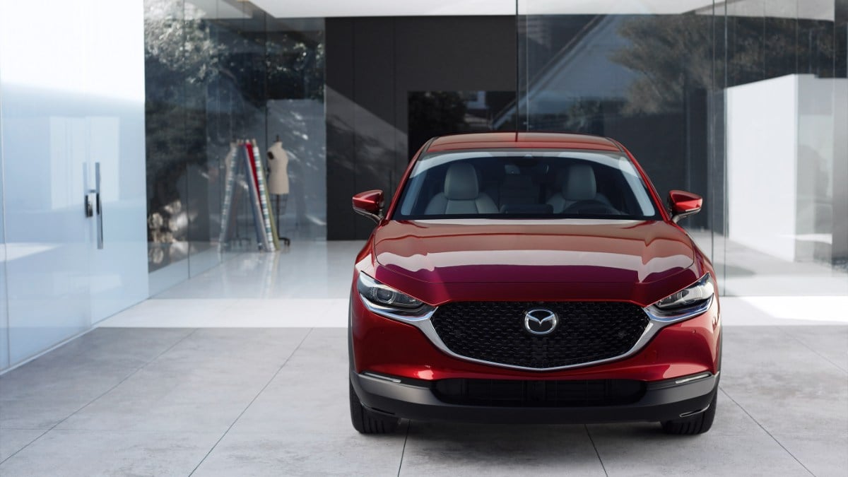 Front view of red Mazda CX-30 compact SUV parked in a modern architectural setting