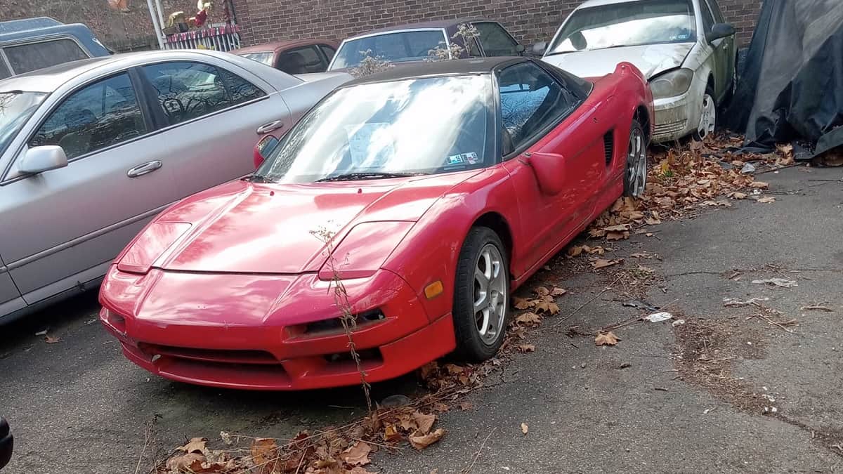 Red 1993 Acura NSX in a body shop parking lot