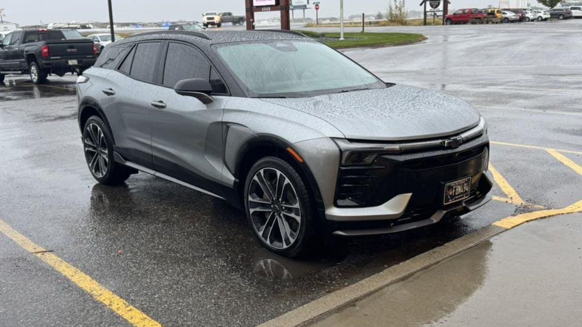 A silver/gray Chevy Blazer EV is parked in a wet parking lot with rain droplets visible on its surface.
