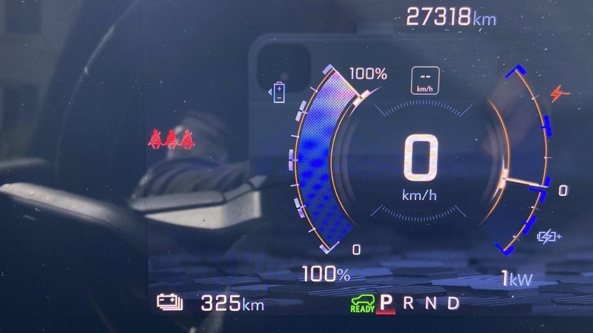 Chevy Silverado EV's display showing 0 km/h speed, battery at 100%, and 325 km range. Red seatbelt warning lights are illuminated, with a total odometer reading of 27318 km.