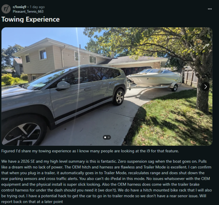 A silver 2026 SE SUV parked in a driveway, towing a boat, with a house and trees in the background, showcasing its towing capabilities.
