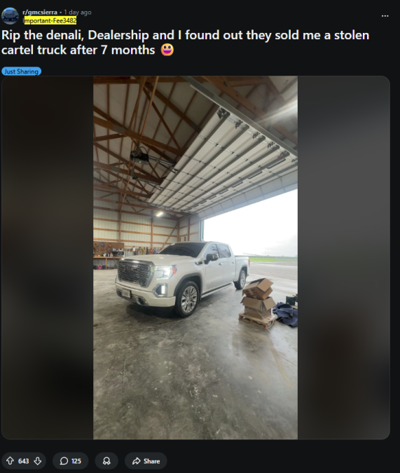A white GMC Denali truck parked inside a spacious hangar, with stacks of boxes and tools nearby, hinting at recent vehicle issues.