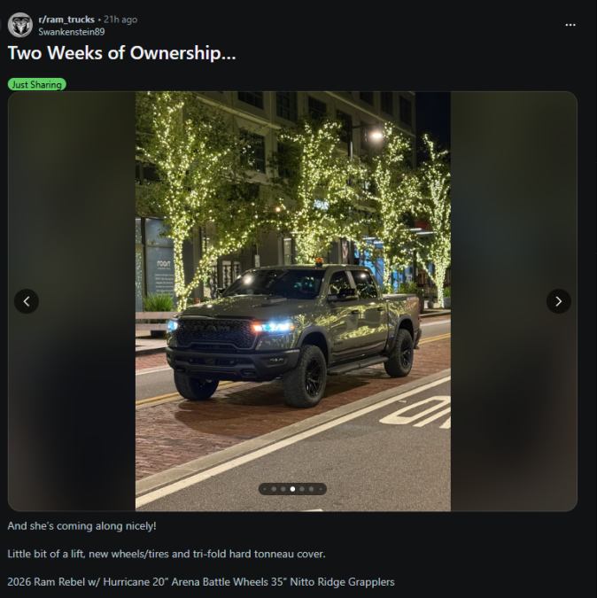 Reddit post showcasing a modified green 2026 Ram Rebel pickup truck parked on a city street at night with decorative tree lights, titled ‘Two Weeks of Ownership