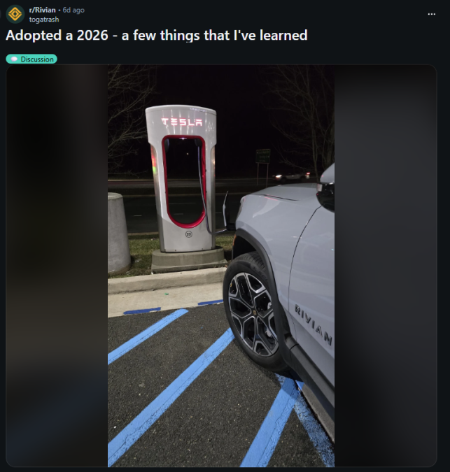 Rivian R1S parked at a Tesla Supercharger station at night, showing compatibility with Supercharger network