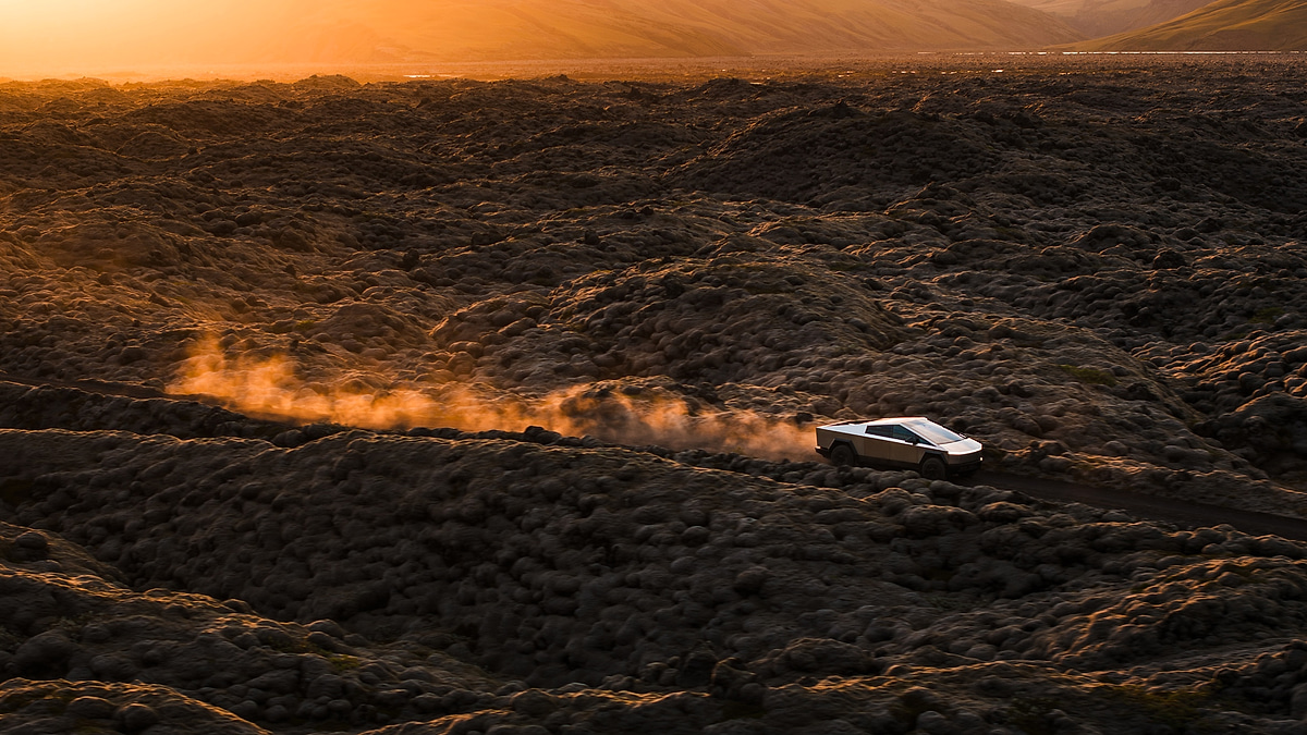 Tesla Cybertruck driving off road with dust trail at sunset aerial view