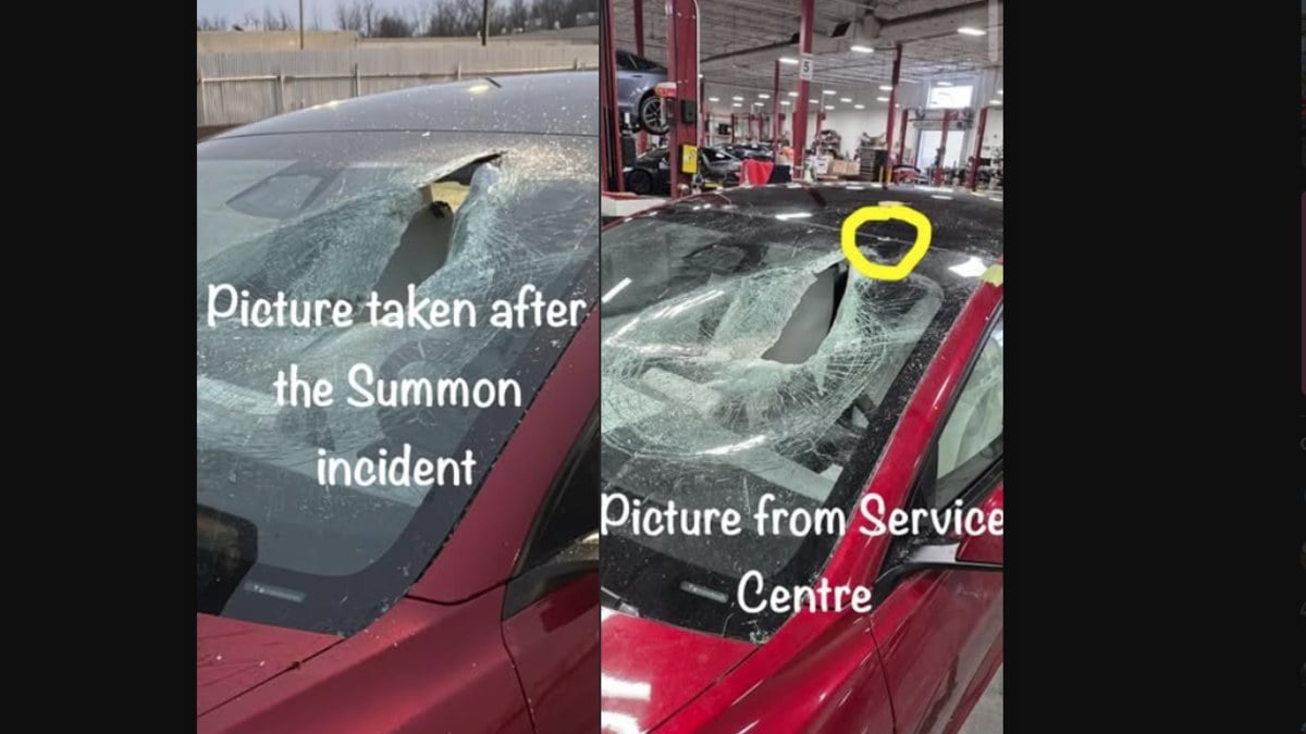 Red Tesla Model 3 at service center with severely shattered windshield, showing extensive glass damage across entire windscreen surface, photographed from front angle.