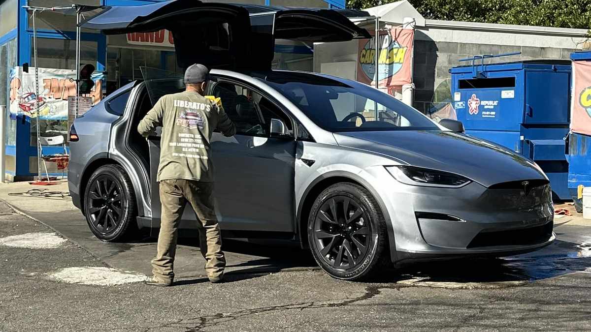 Tesla Model X with falcon wing doors open at car wash
