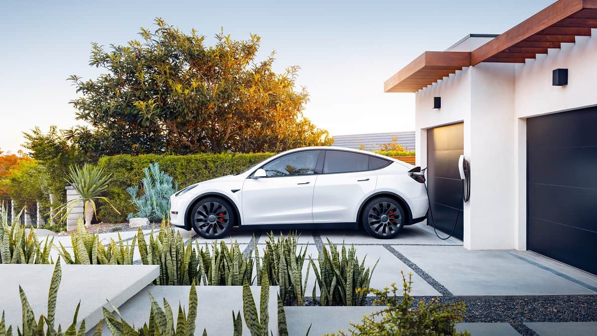Tesla Model Y charging in the driveway of a residential home