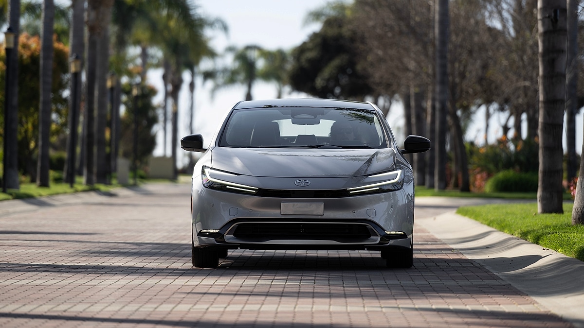 Front view of Toyota Prius Prime on quiet residential street with palm trees