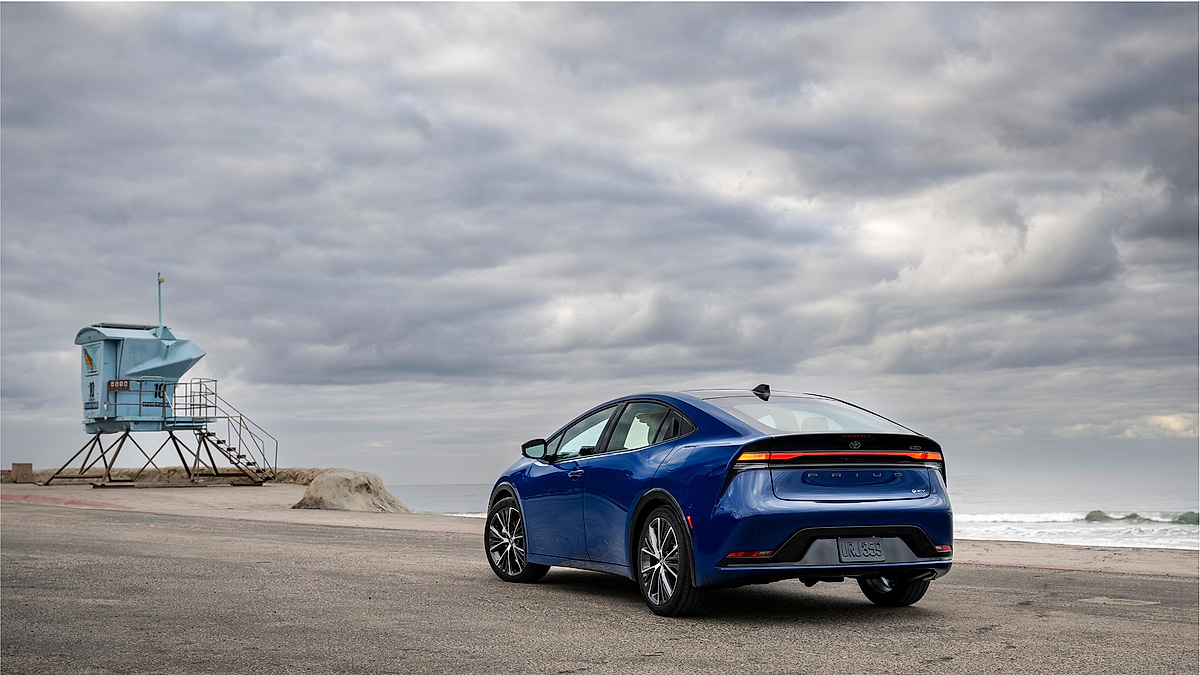 Blue Toyota Prius rear view parked near beach with cloudy sky
