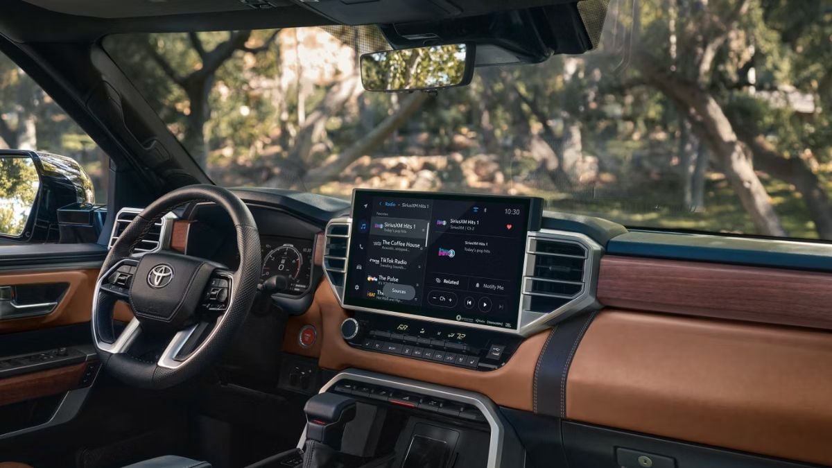 Luxury Toyota Tundra interior with a sleek dashboard featuring an infotainment system. The steering wheel and trim have a blend of black and brown leather.