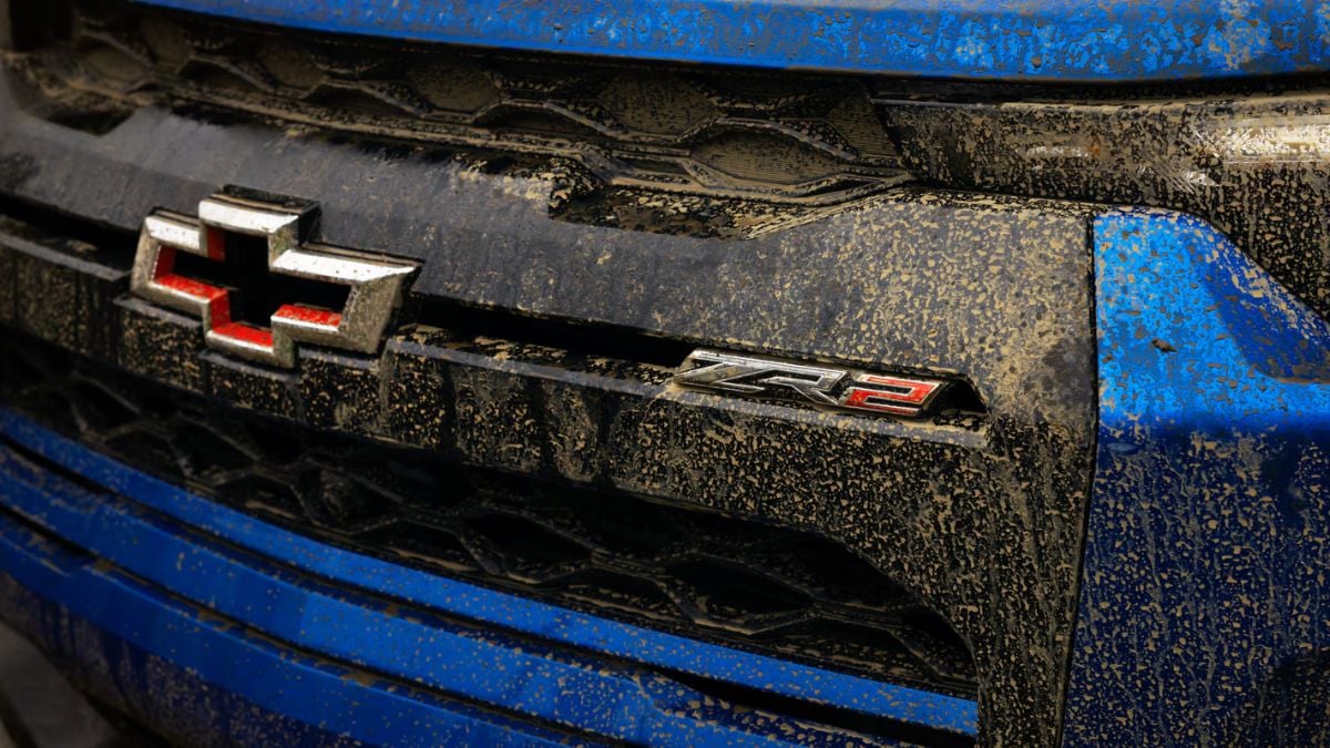Muddy blue Chevrolet ZR2 badge with dirt-splattered grill, showcasing off-road ruggedness