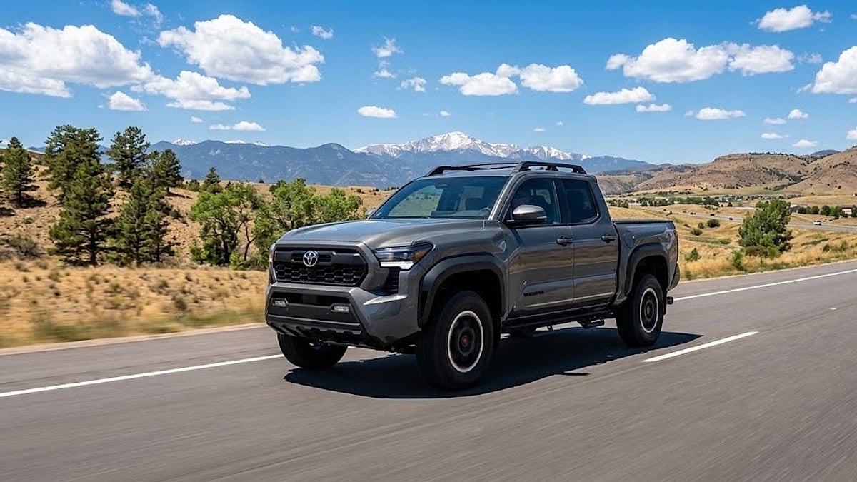 A 2025 grey Toyota Tacoma drives along a highway with the Rocky Mountains and Pikes Peak visible near Parker, Colorado