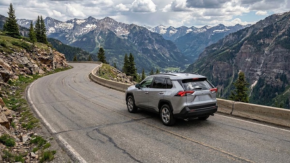 A 2025 Toyota RAV4 navigates a steep, winding Colorado mountain road surrounded by rugged alpine peaks
