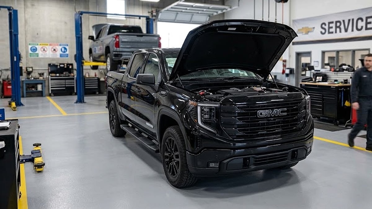 A 2026 GMC Sierra Elevation with its hood raised inside a busy dealership service bay for technical powertrain evaluation