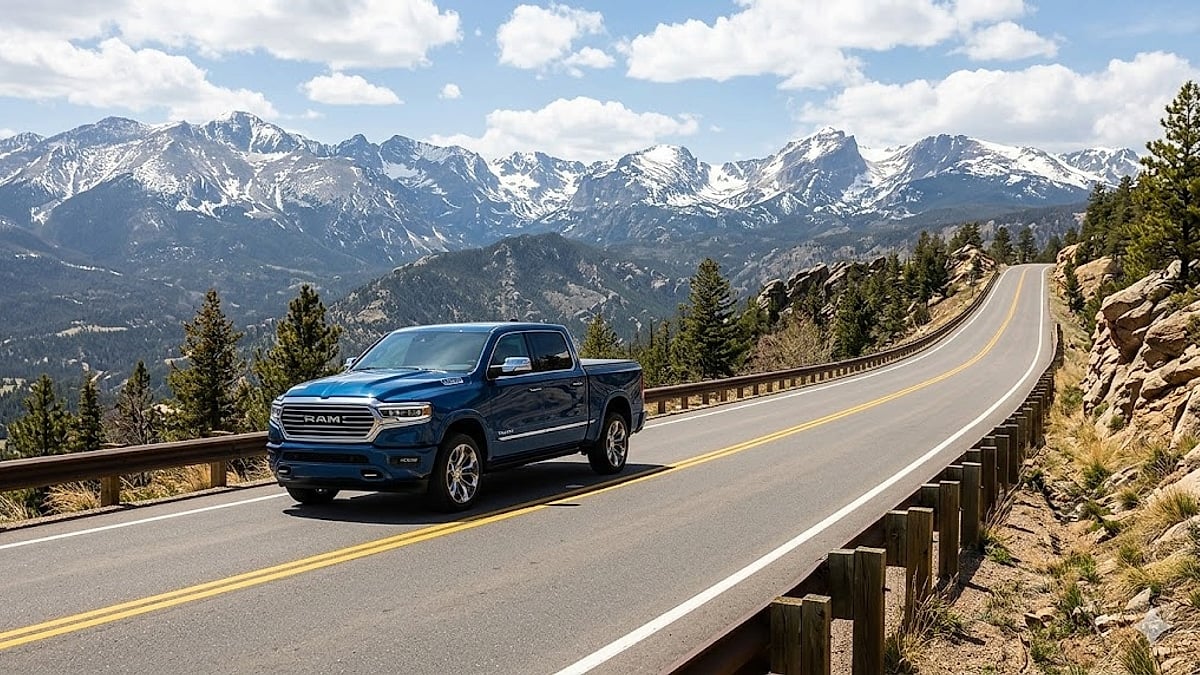 A 2026 Ram 1500 Limited Longhorn drives up a winding Colorado mountain road with snow-capped peaks in the background