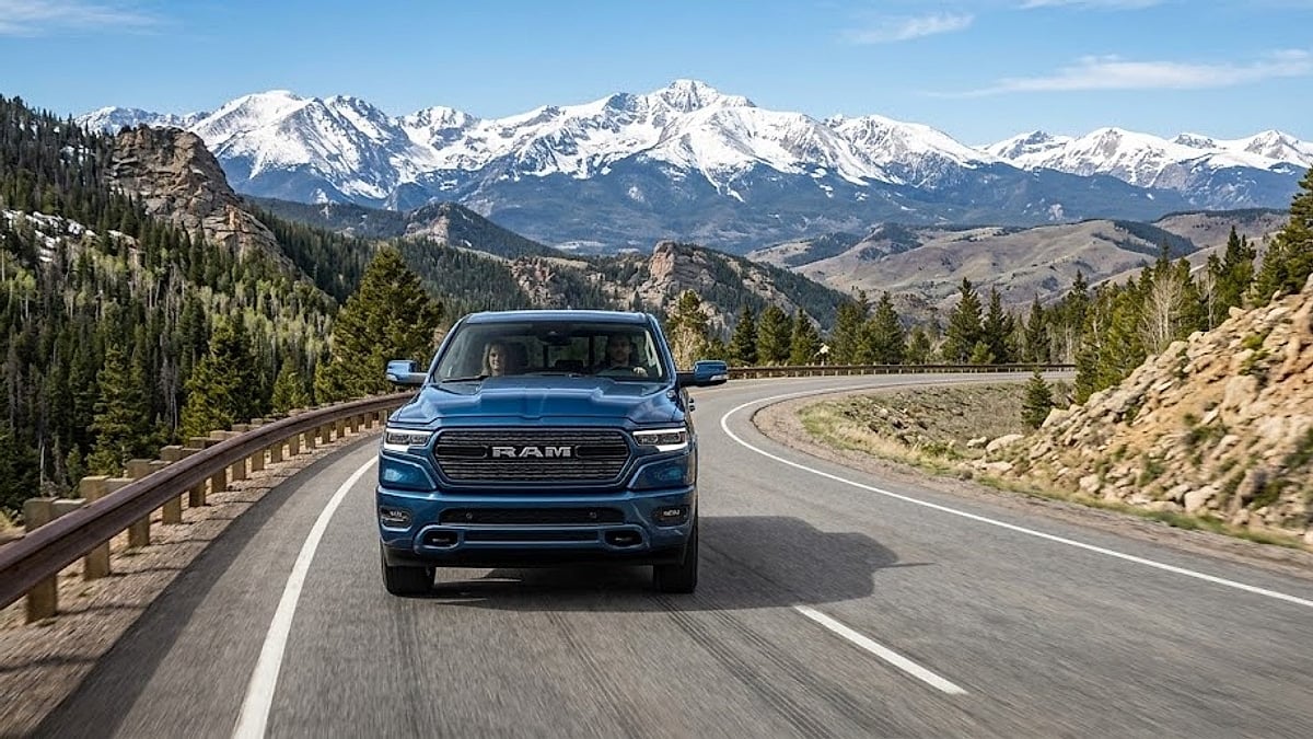 A 2026 Ram 1500 pickup truck drives along a scenic, curving high-altitude mountain highway near Denver, Colorado