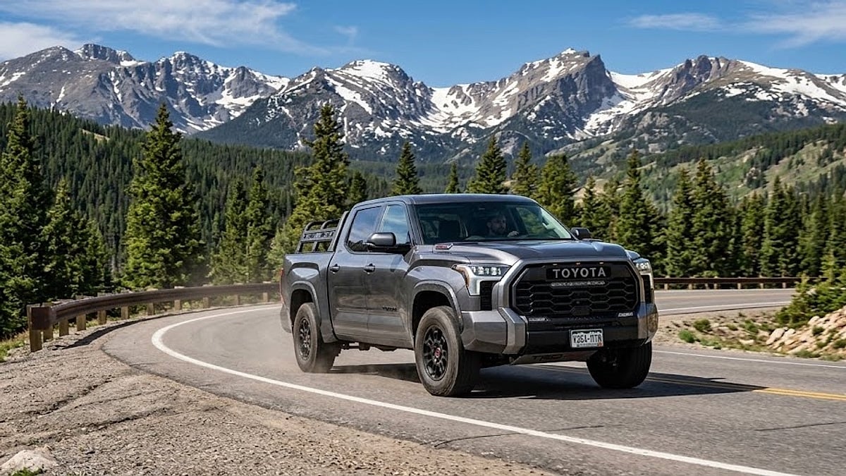 A 2026 Toyota Tundra navigates a high-altitude Colorado mountain pass road, showcasing truck durability and performance against rugged peak backdrops