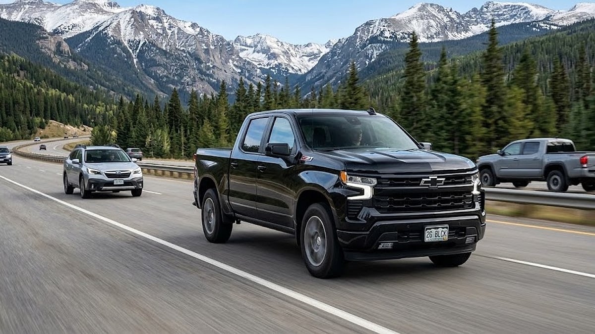 A black 2026 Chevrolet Silverado 1500 cruises a Colorado highway with other traffic and mountains visible