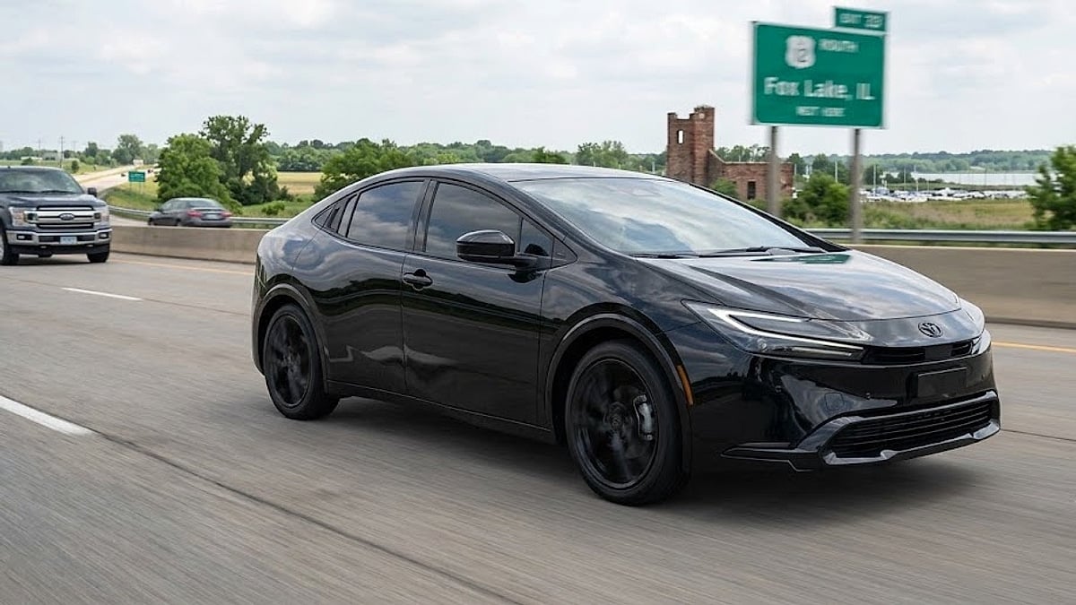A black 2026 Toyota Prius XLE Nightshade drives on an Illinois highway near a sign for Fox Lake, IL