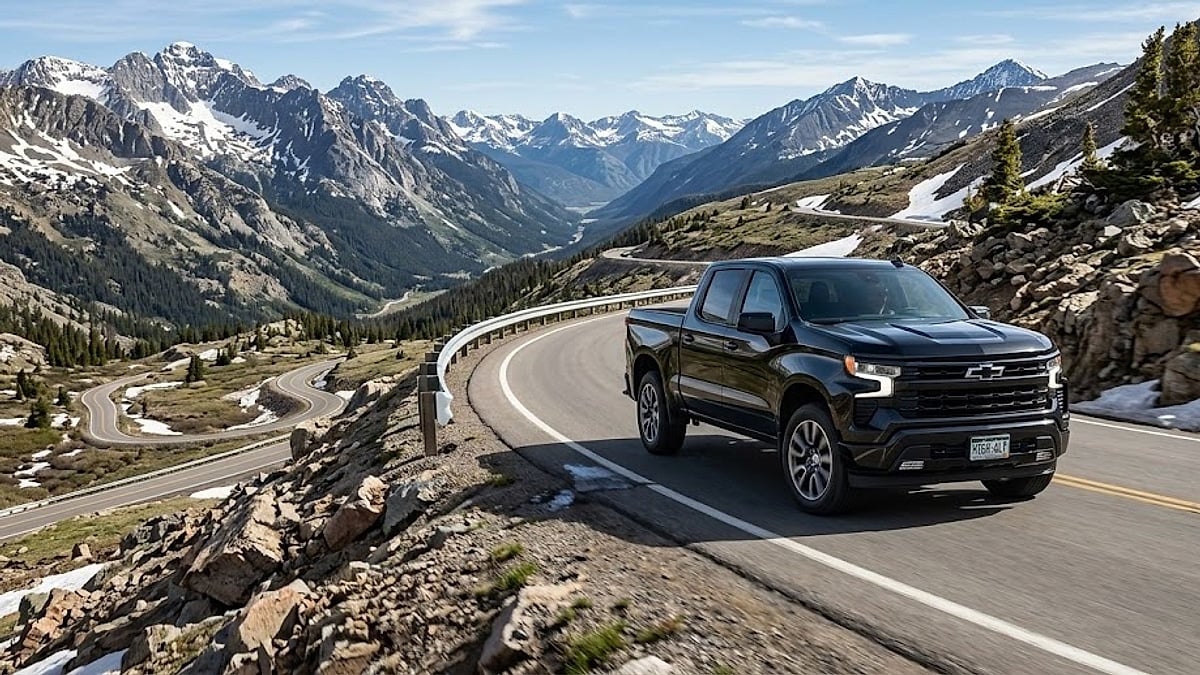 A black Chevy Silverado navigates a winding mountain road through the snowy peaks of Colorado, showcasing high-altitude performance