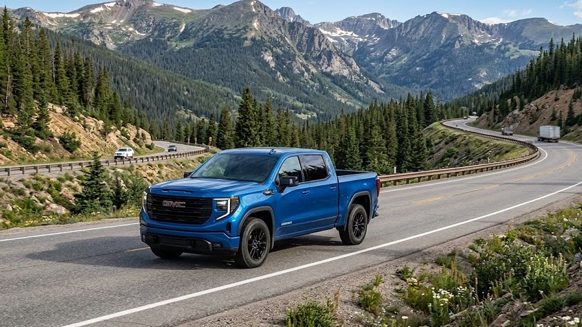 A blue 2026 GMC Sierra Elevation pickup truck actively climbing the steep, scenic Interstate 70 highway up Vail Pass, Colorado