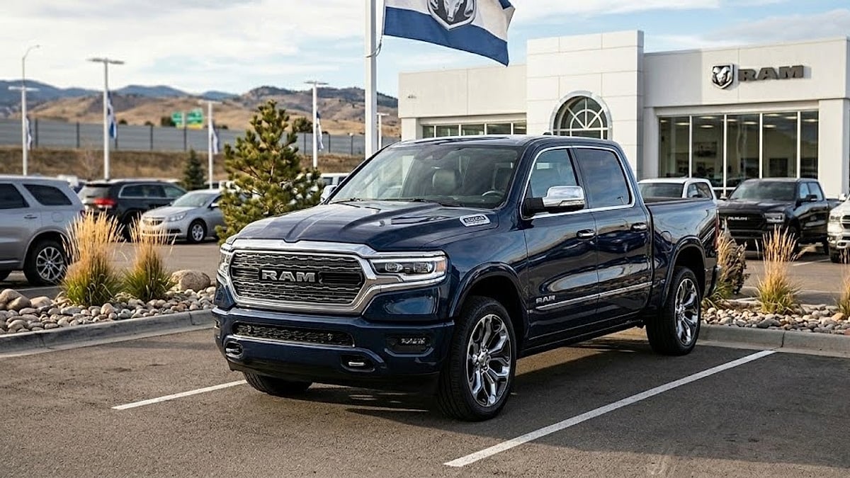 A deep blue 2026 Ram truck for sale parked on a dealership lot under a Colorado sky with mountains in the background