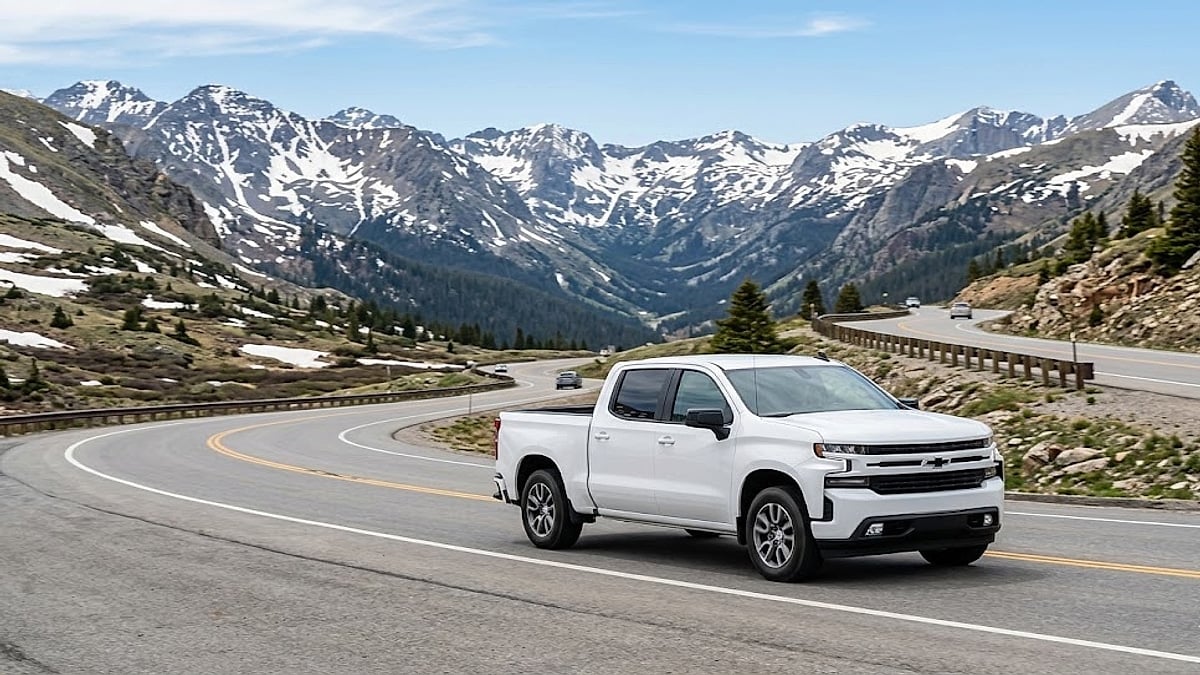 A white 2021 Chevy Silverado crew cab truck navigates a winding high-altitude mountain pass road in the Colorado Rockies